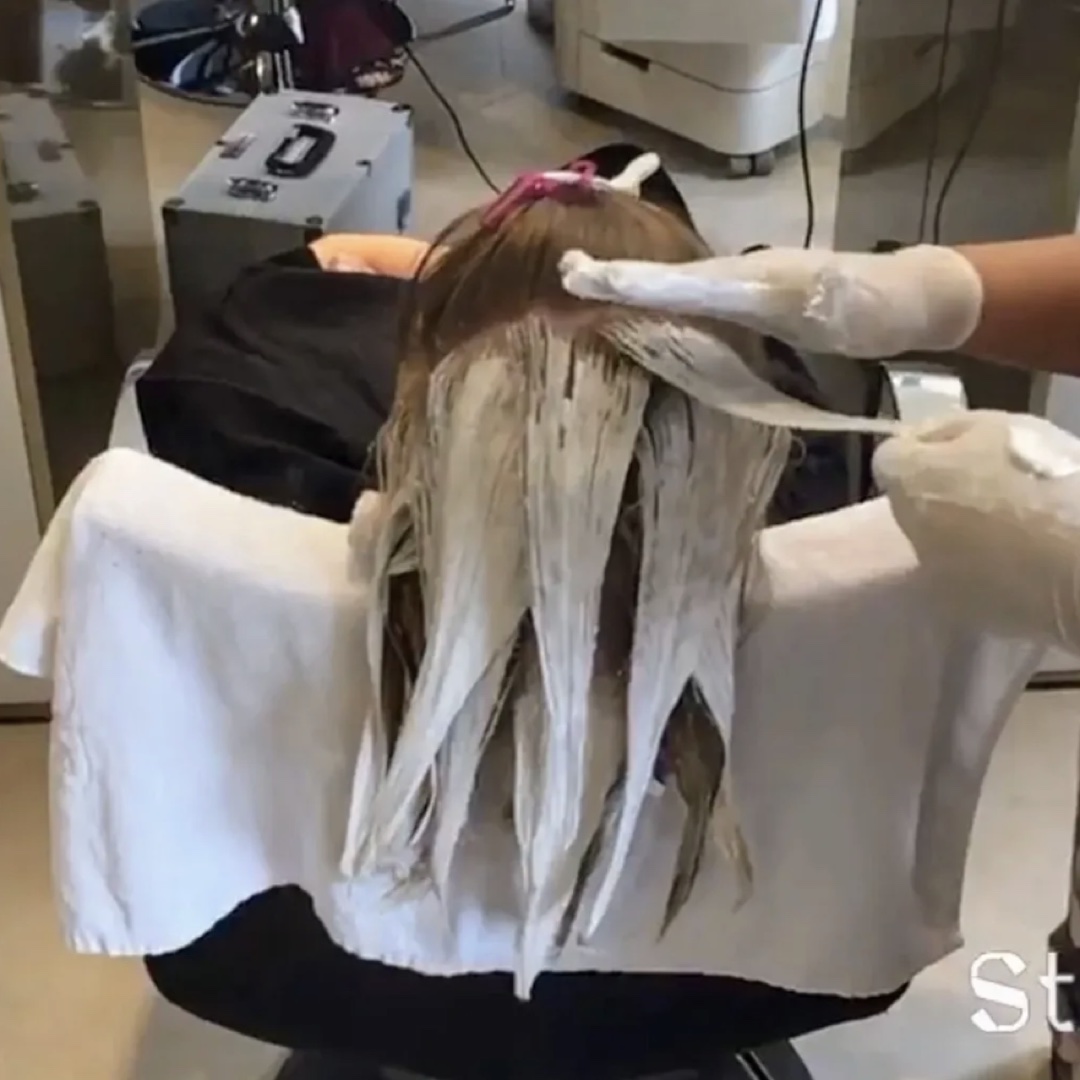 Detalhe das mãos aplicando a técnica em mechas separadas